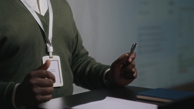 Slowmo midsection shot of unrecognizable African American male speaker wearing name badge standing behind lectern and giving speech, participating in conference