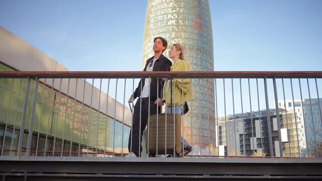 Joyful couple strolls with their luggage, sharing smiles and laughter on their travel adventure together. Their excitement for the journey ahead is evident as they walk hand in hand.
