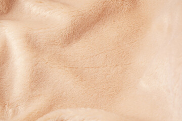 Fototapeta premium Detailed view of warm soft beige fluffy textile material showing subtle folds and shadows