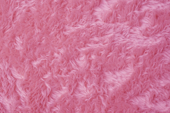 Soft fluffy vibrant pink faux fur fabric texture background creating a cozy intricate pattern