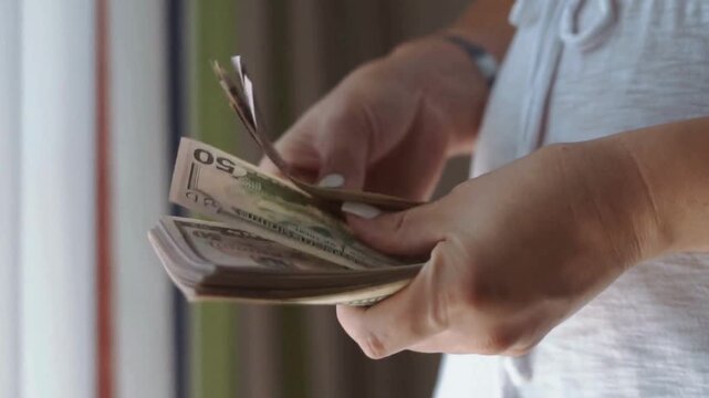 Close up of female hands counting a stack of us dollar banknotes
