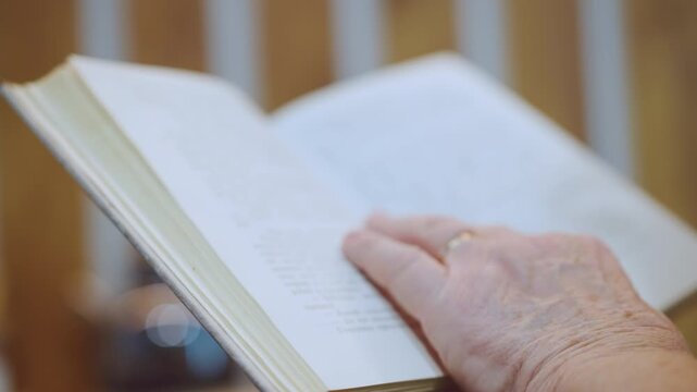 Grandmother softly flipping through her cherished magazine pages with gentle hands. Mature woman carefully examining articles in her favorite morning newspaper with calmness and focus