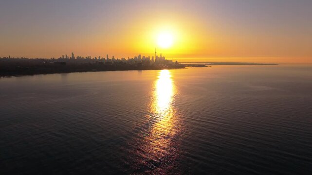 Aerial drone footage of the Toronto skyline at sunrise, glowing with warm golden light over Lake Ontario in crisp 4K resolution.

