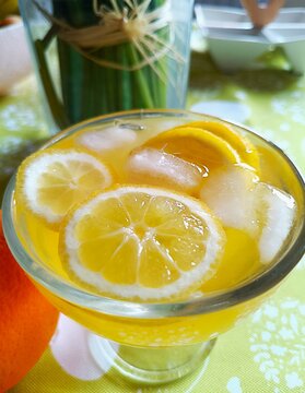 Lemon slices in orange juice with ice cubes in the glass fresh citrus fruit summer background