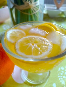 Lemon slices in orange juice with ice cubes in the glass fresh citrus fruit summer background