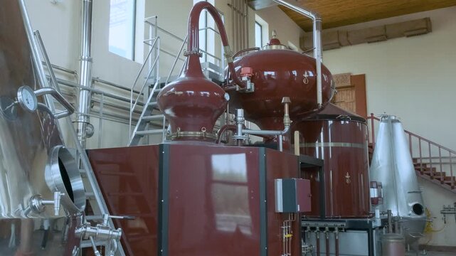 Brandy distillery with large red fermentation tanks with copper piping and gauges. Distiller for alcohol production of high-quality spirits in Armenia. Food and beverage technology