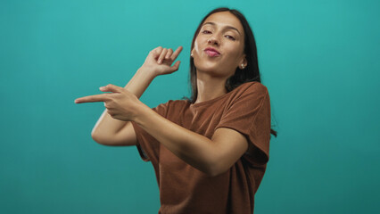 Woman pointing fingers with animated hand gestures in teal studio, facing right and showing...