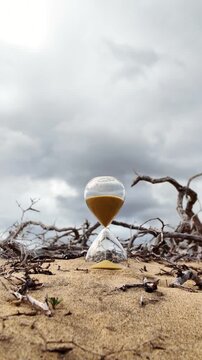 Hourglass with golden sand measuring the passing time in a dry and arid landscape, a metaphor for climate change, global warming, desertification and the irreversible passage of time
