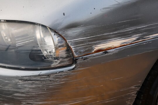 Damaged silver car showing extensive scratches and rust