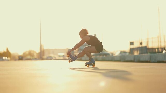 Young athletic woman performing trick on roller skates at sunset