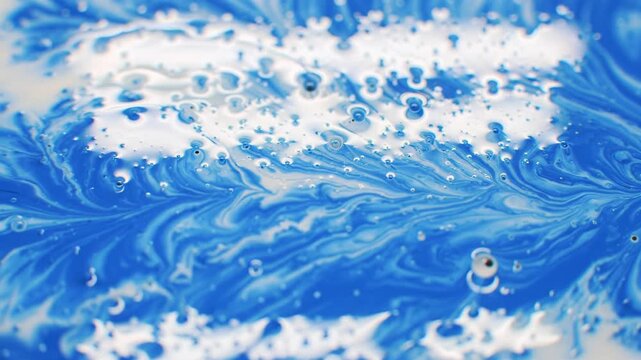 an extreme close-up macro video of vibrant blue and pure white abstract fluid art, swirling into intricate marbling patterns with glossy, reflective surfaces and soft studio lighting, showcasing a