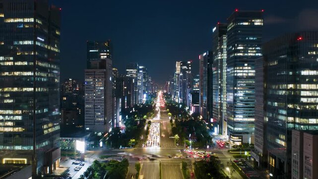 Elevated time-lapse video of a modern city transforming from vibrant dusk to deep night, car light trails streak across multi-lane roads, thousands of windows illuminate, revealing an expansive
