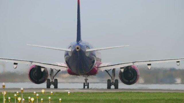 Colorful passenger aircraft accelerating on runway during takeoff roll, rear close up with engines at full thrust in hot sunny conditions, intensified heat haze distortion, slow motion aviation scene
