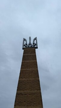 Tryzub on a pedestal against cloudy sky