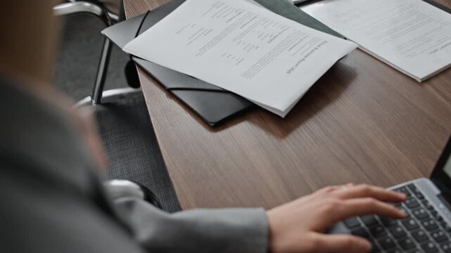 Male Caucasian boss communicating with anonymous employee while woman listening to him and taking notes on laptop during meeting in office