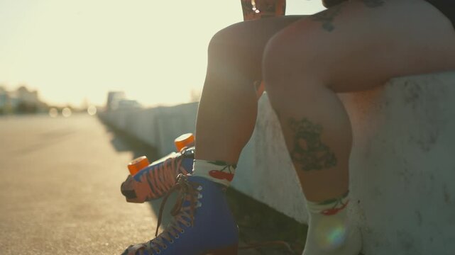 Tattooed woman putting on roller skates at sunset