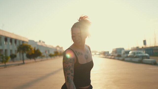 Tattooed asian woman rollerskating backwards at sunset