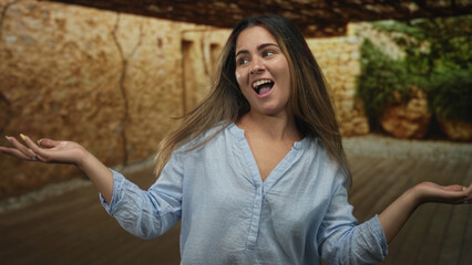 Fototapeta premium Woman with hands raised in studio, smiling with open mouth and expressive gesture; joyful celebration.
