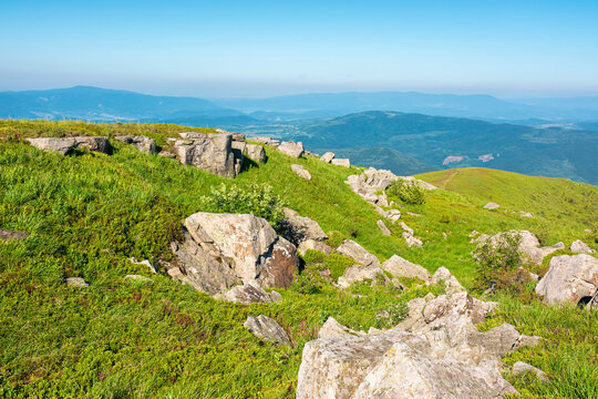mountain landscape with stones and grass. view of carpthian mountains in summer. white sharp stones on the rolling hills on top of mountain range under blue sky
