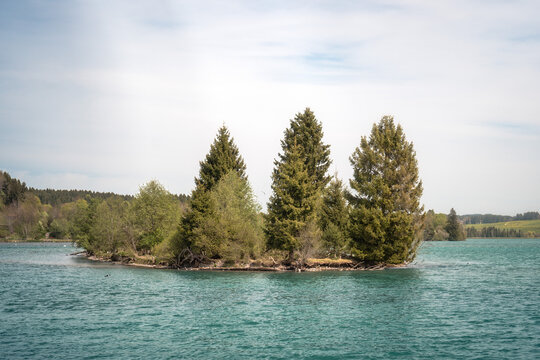 A scenic small island with evergreen trees on the turquoise Lechsee reservoir (Urspring Lechsee) in Bavaria, ideal for travel themes