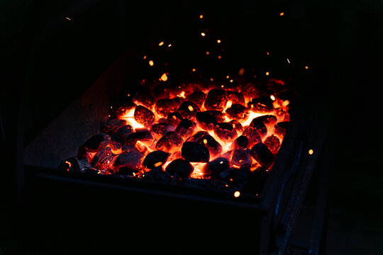 Glowing Charcoal Embers In Grill Heat And Sparks, Closeup Of Redhot Coal Bed Inside Metal Grill, Scattered Sparks Rising, Smoky Aroma, Preheating