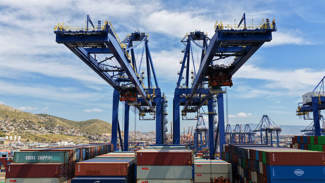 Aerial drone photo of container ship docked in terminal of port of Perama during huge cranes loading - unloading from truck size ship, Attica, Greece