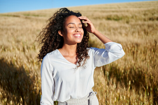 Young woman enjoying sunshine in golden wheat field