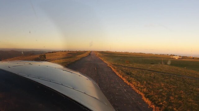 Pilot View from Small Aircraft on Final Approach to Rural Airstrip at Golden Hour with Scenic Countryside Landscape. General Aviation Plane Landing on Remote Runway at Sunset