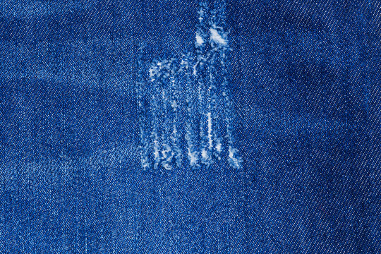 Denim fabric shows signs of wear in blue color with faded area near the center