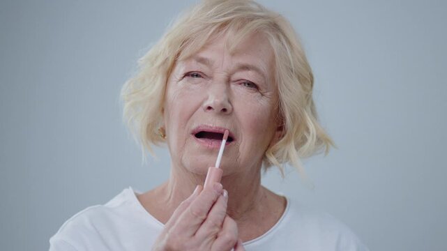 Natural beauty and comsetics concept. Portrait of appealing senior woman doing nude make-up smiling on camera isolated on light background.