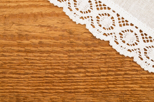 White lace sits on a wooden surface showing texture and details of the materials used in a home setting