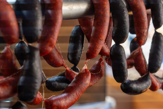 Traditional cured red chorizo and dark blood sausages hanging in a Spanish deli or market.