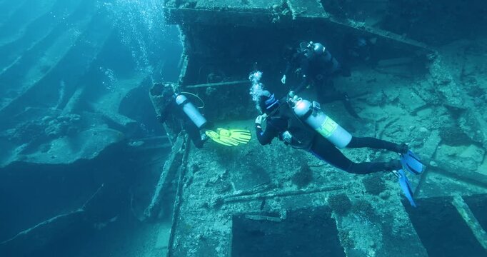 Divers explore the wreck of the SS Thistlegorm. Top diving wreck dives. Swimming over motorbikes and other cargo in hold of Thistlegorm shipwreck in the Red Sea, Sharm el Sheikh, Egypt.