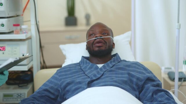 Sick miserable exhausted afro-american guy lying in private clinic hospital suffering covid-symptoms. Caucasian doctor in face protection caring for his patient. Healthcare. Quarantine.