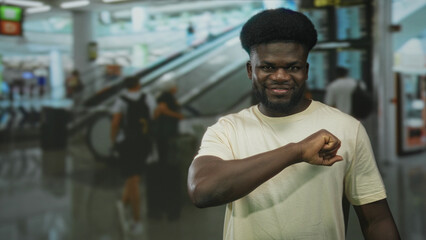 Obraz premium Young man holds fist to camera in airport terminal wearing casual white t shirt and smiling; confidence.