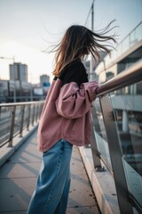 Obraz premium Woman silhouette on urban bridge with windswept hair and casual jacket