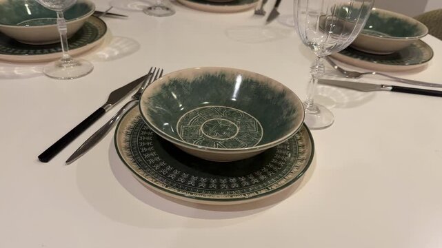 Table setting with green patterned dinnerware and glassware for home dining background