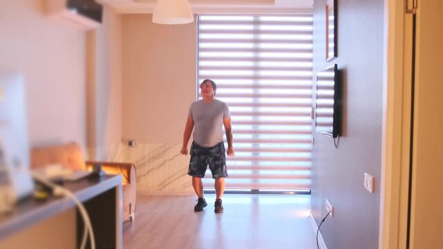 Man performing jumping jacks at home, dynamic cardio workout improving endurance, coordination and fat burn, bodyweight exercise for fitness routine in indoor environment
