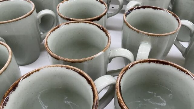 Ceramic mugs arranged in rows create a pattern of rustic kitchenware, ideal for backgrounds