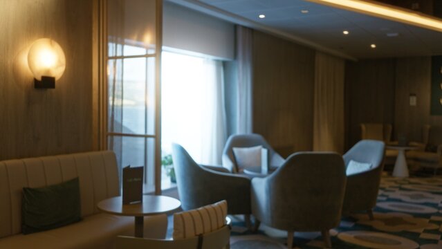 Soft blurred hotel lounge with shallow focus on curved chairs, tables and warm wall lighting, interior; background backplate copyspace calm.