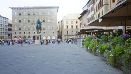 Fototapeta premium Blurry plaza with soft bokeh and shallow focus showing a distant equestrian statue and cafe terrace in a plaza; background backdrop copyspace calm.