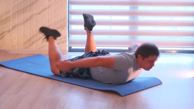 Man performs superman back extension on mat, lifting arms and legs to strengthen lower back, core and posterior chain. Effective bodyweight exercise for posture, stability and home workout routine