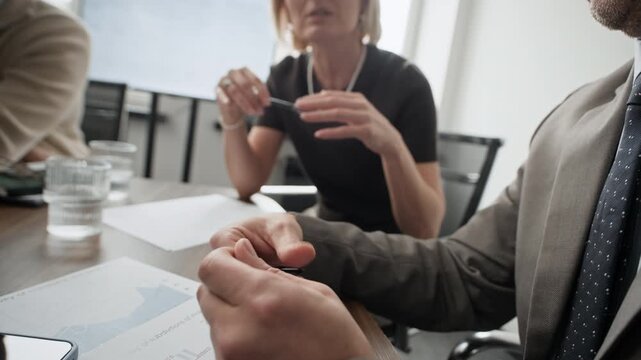 Close up of anonymous man and woman gesticulating in air while discussing business strategy during meeting in office