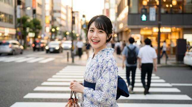 夕暮れの街中で横断歩道を渡り振り返る浴衣姿の女性のデート風景