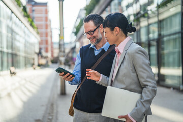Business professionals collaborating using mobile device in city © Miljan Živković