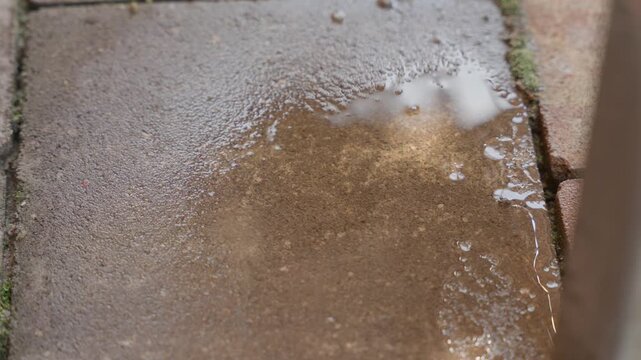 water drops falling on pavement close up for leak or rain concept with wet surface and splash detail