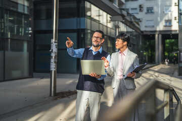 Fototapeta premium Business partners discussing project details on city street