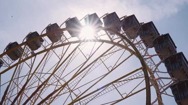 Traditionelles Riesenrad mit Holzgondeln und Sonnenstrahlen auf einem Volksfest