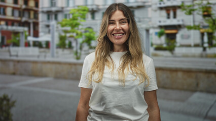 Fototapeta premium Woman with closed eyes in white tshirt standing on street in front of building, relaxed posture and neutral expression; serenity mindfulness.