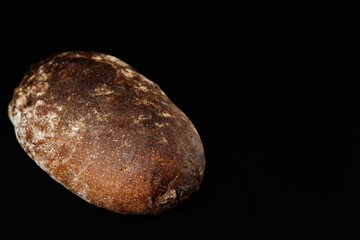 Naklejka premium Rustic sourdough loaf of artisan bread with deep crust on black background for bakery use